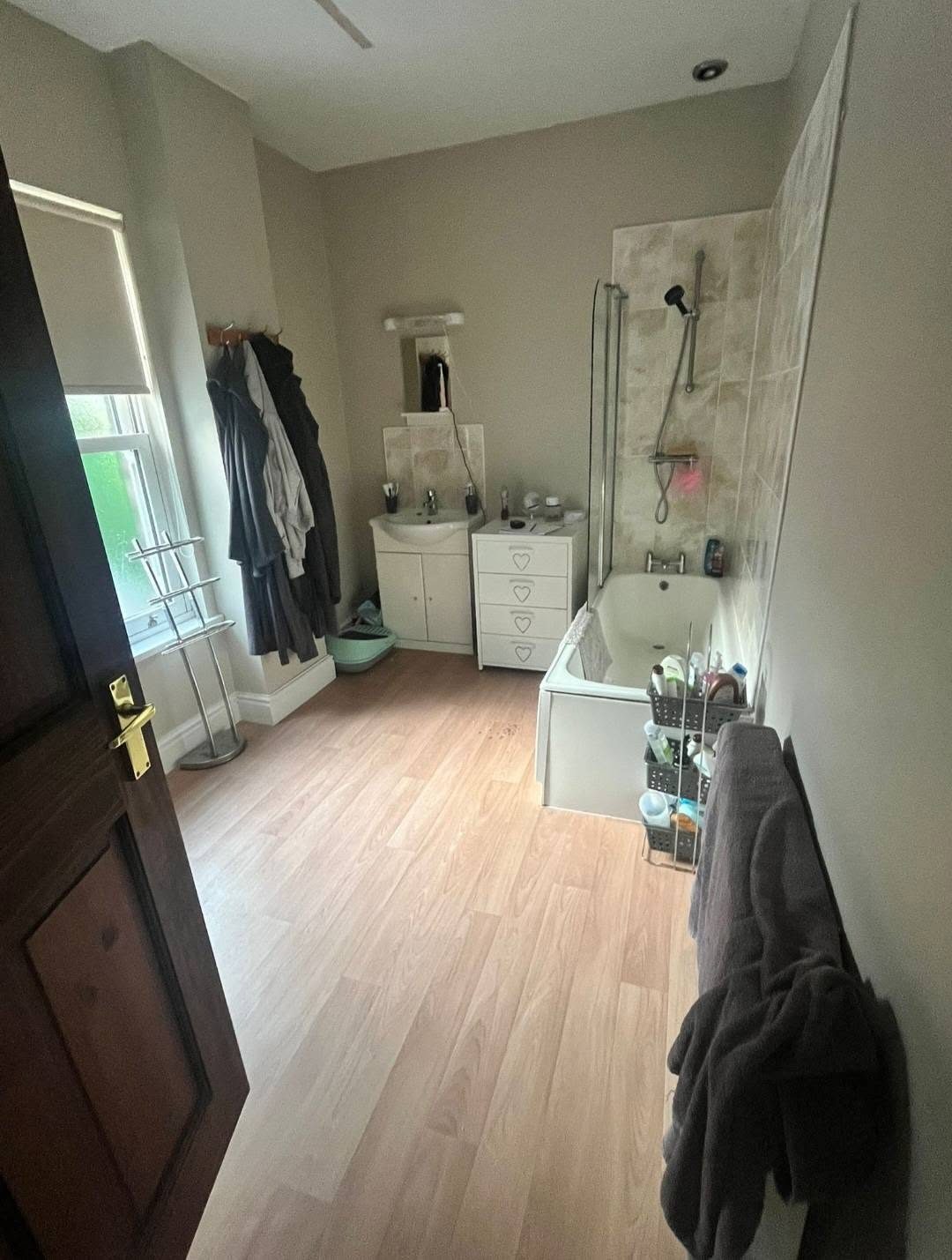 Before: dated family bathroom with a corner bath and laminate floor