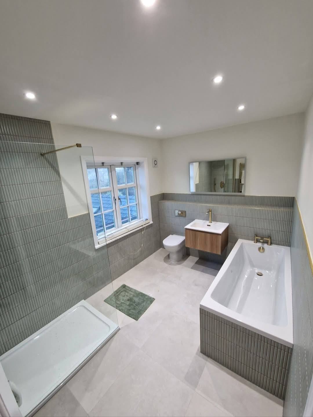 Family bathroom with sage stacked tiles and brass fittings