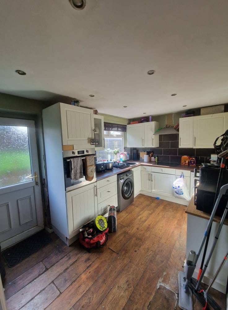 Before: the old kitchen with worn units and dark flooring